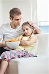 Father convincing daughter to eat wheel shape snack pellets