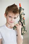 Side view of a young boy holding toy gun