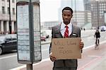 Young businessman holding "Will Work for Food" sign at street