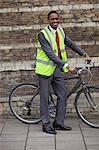 Happy young male engineer with bicycle against brick wall