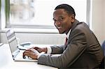 Portrait de l'heureux homme d'affaires américain utilisant un ordinateur portable au bureau