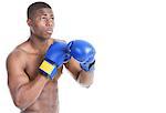 Young boxer wearing boxing gloves in fighting stance over gray background