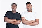 Portrait of two African American male friends with arms crossed over gray background