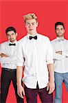 Portrait of a young man standing in front of male friends over red background