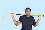 Portrait of an African American man holding hockey stick over blue background