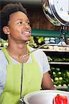 African American male store clerk weighing bell pepper