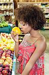 Side view of African American woman smelling fresh orange at supermarket