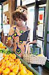 Afroamerikanische Frau in traditioneller Kleidung für Früchte im Supermarkt einkaufen