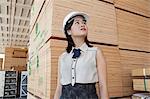 Junge weibliche Industriearbeiter Wegsehen mit gestapelten Holzbohlen im Hintergrund