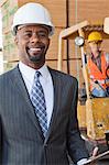 Portrait of African American male engineer smiling with female worker in background