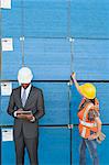 African American male engineer working on tablet PC while female industrial worker checking wooden planks