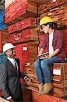 Female industrial worker and male engineer smiling while looking at each other at timber yard