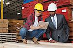 Female industrial worker showing something on tablet PC to male engineer