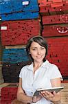 Portrait of an attractive businesswoman using tablet PC with stacked wooden planks in background