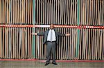 Portrait of happy African American businessman standing arms outstretched in front of thin veneer sheets