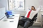 Young Indian businessman relaxing in chair at office desk