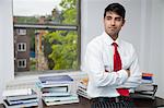 Portrait of a confident businessman with arms crossed looking away in office