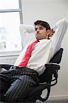 Young Indian businessman contemplating while sitting in office chair