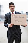 Portrait of young Indian businessman holding 'Will Work for Food' sign