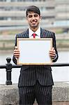 Portrait of young Indian businessman holding blank sign