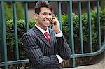 Young Indian businessman on call against fence