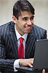 Young smiling Indian businessman using laptop