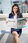 Portrait of a smart Indian businesswoman holding newspaper as she sits outdoors