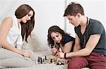 Young friends playing chess on sofa