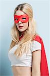 Portrait of young woman wearing superhero costume against blue background