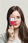 Portrait of young woman with red lips holding ice cream bar against gray background