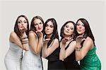 Five young women blowing kisses over gray background