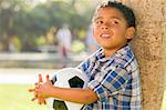 Mixed Race Boy Holding Soccer Ball in the Park Against a Tree.