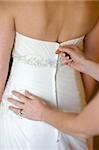 bridesmaid zips up the wedding dress of the bride