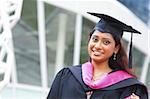 Stock image of Indian female graduate student standing in front school buiding