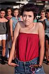 Lonely girl with hunched shoulders near group of people