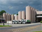 trucks in front of some large silos belonging to a milk powder factory