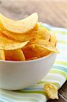 potato chips in a white bowl on a wooden table