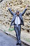 happy businessman dancing in the street against the wall
