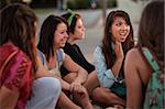 Disgusted teenage girl sitting on the ground talking with friends