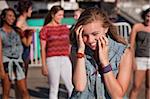 Shy giggling teenage girl covering her face at carnival