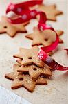 gingerbread stars with red christmas ribbon on bakery paper