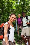 group of man and women during hiking excursion in woods, with woman looking at camera and smiling. Waist up