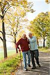 Seniors hommes marchant sur le chemin bordé d'arbres en automne, Lampertheim, Hesse, Allemagne