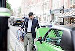 Man charging electric car on street