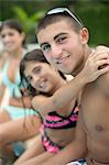 Brother and sister hugging by pool