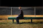 Pensive young man sitting on bleachers at night