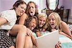 Girls looking at digital tablet, sticking out tongues