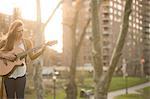 Young woman playing guitar in the park