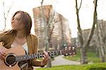 Young woman playing guitar outdoors