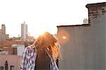 Young woman shaking hair on city rooftop